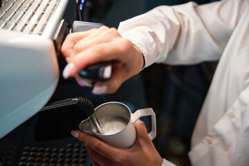 Barista prepares coffee with milk foam in a coffee machine