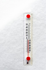 A white thermometer with a red scale lies on white snow. Winter. Temperature