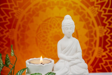 Close up of white marble figurine of Siddhartha Gautama, known as Buddha, with candle burning and...