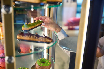 Waitress takes out an eclair from a transparent display case