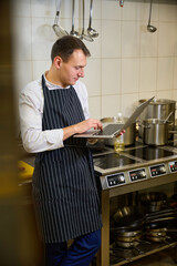 Kitchen employee sits with a laptop at the stove