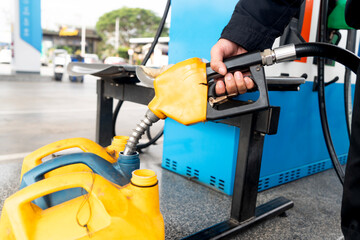 Employee filling up fuel into plastic gallons at the service station - obrazy, fototapety, plakaty