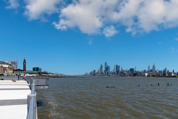 Panoramic view from Hudson River Waterfront Pier in Jersey City, NJ, USA towards Hoboken Terminal and Midtown Manhattan, New York City with skyline of skyscrapers on other side of the Hudson river