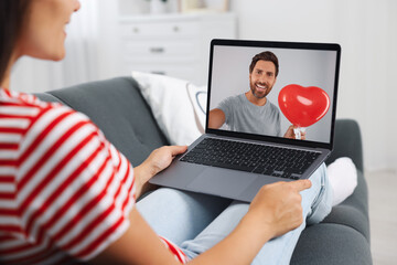 Long distance love. Woman having video chat with her boyfriend via laptop at home, closeup