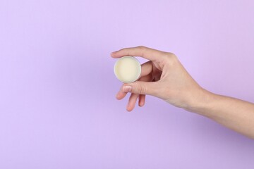 Woman with lip balm on violet background, closeup