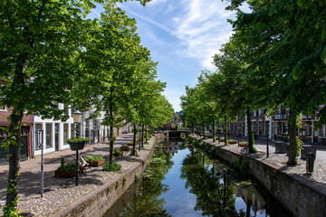 Fototapeta na wymiar View of bridge and street on Havik canal in Amersfoort, the Netherlands, with historic buildings and green trees reflected in the tranquil water of the canal