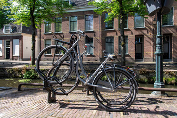 Fototapeta na wymiar Close up view of two bicycles parked in an angle in a bicycle rack along a typical canal in the Netherlands with canal houses on other side of the water