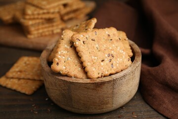 Cereal crackers with flax and sesame seeds in bowl on wooden table, closeup