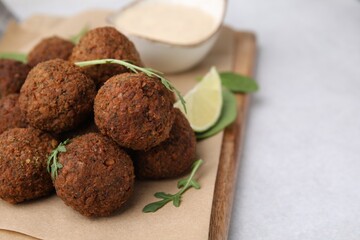 Delicious falafel balls and arugula on light table, closeup. Space for text