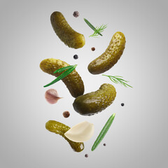 Tasty pickled cucumbers, herbs and spices falling on light grey background