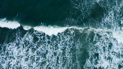 Overhead view to blue stormy ocean waves with white foam.