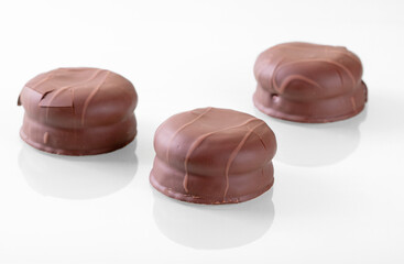 Gorgeous reflection of chocolate-coated marshmallow on white mirrored surface