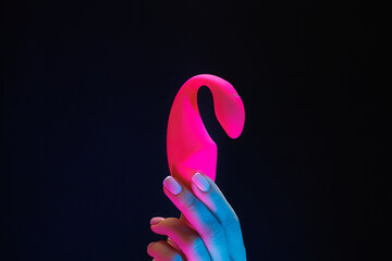 Close-up of a girl holding a red-colored sexual entertainment toy. Sex toy clitoral vibrator on a...