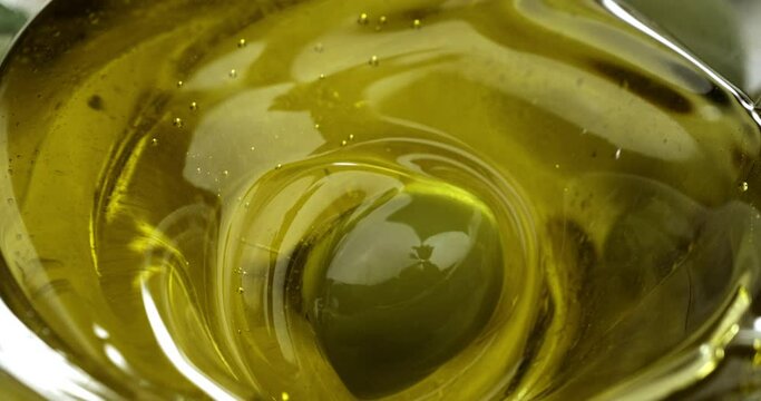 Super slow motion macro of fresh ripe olive is falling in bio organic golden liquid extra virgin olive oil with splashing drops on ripe olives at 1000 fps.