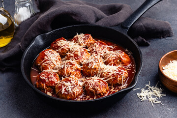 Beef meatballs with tomato sauce and parmesan cheese on gray background, close up