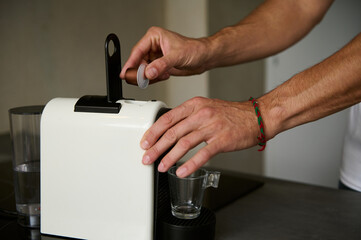 Close-up male hand prepares espresso coffee, inserting capsule with grinded arabica inside a coffee...