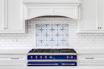 A kitchen detail with a blue and stainless steel stove, subway and mosaic tiled backsplash, and...