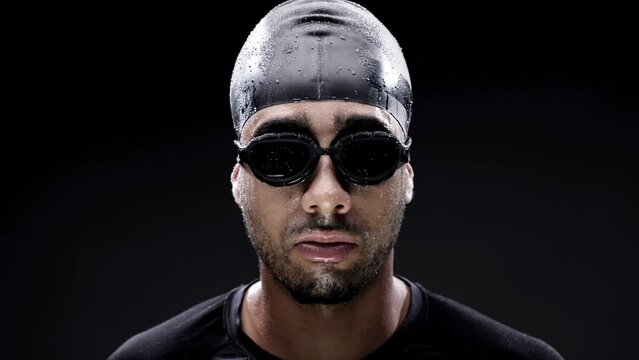 Swimmer, face and goggles, man and sports with fitness, workout and determination on black background. Challenge, competition and confident athlete in training, exercise and portrait for swimming