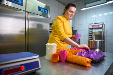 Smiling pastry cook arranging cake molds on baking tray