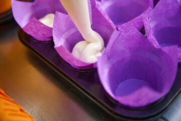 Disposable paper baking molds being filled with pastry dough