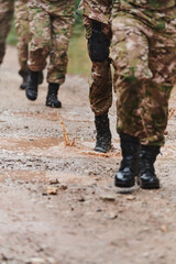 Close up photo, the resilient legs of elite soldiers, clad in camouflage boots, stride purposefully along a hazardous forest path as they embark on a high-stakes military mission