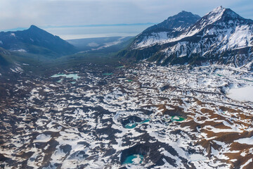 Snow covered Red Glacier in Lake Clark National Park in Alaska. Glacial ponds, crevasses, snow and ice. Red glacier is covered with ash and debris from Mount Iliamna Volcano. Cook Inlet in distance.