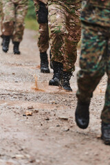Close up photo, the resilient legs of elite soldiers, clad in camouflage boots, stride purposefully...