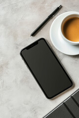 Eine elegante, zeitgenössische Büroschreibtischansicht, ein Smartphone, Kaffeetasse, Notizblock und Bleistift auf einem Marmorhintergrund