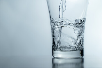 pouring water into glass on table, glass of water with splash isolated on white background. clean...