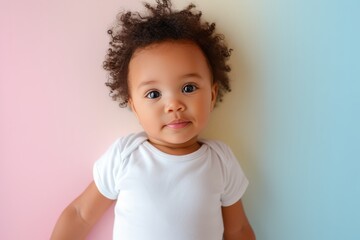 Naklejka premium Baby Girl With Curly Hair Wearing White Bodysuit on pastel background. 