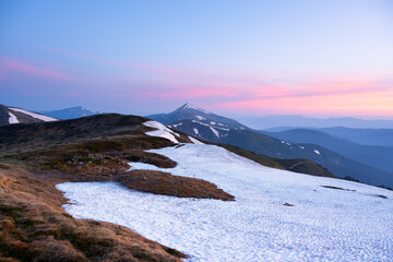 Morning in spring mountains with snow-capped hills and pink sunrise sky. Ukrainian Carpathians. Landscape photography