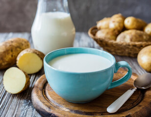 Obraz na płótnie Canvas Potato milk. A cup with milk and potato tubers. Alternative plant milk