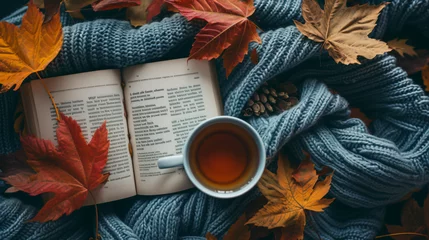 Poster A flat lay of a cozy autumn reading setup including a warm knitted blanket a cup of hot tea an open novel and colorful fall leaves scattered around. © Lucas
