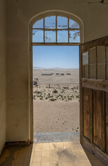 desert view through forsaken hospital door at mining ghost town in desert, Kolmanskop,  Namibia