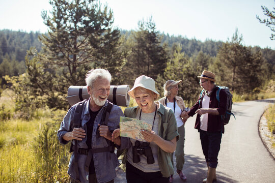 Group of senior hikers with backpacks and map enjoying nature trail