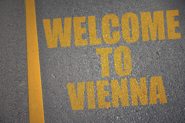asphalt road with text welcome to Vienna near yellow line.