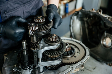 a disassembled gearbox in the hands of an experienced car mechanic who repairs broken mechanisms...
