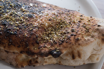 Calzone pizza close up on spices, crust from a Neapolitan oven
