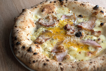 Pizza with Carbonara with bacon and egg, fermented dough baked crusts close-up , Neapolitan oven