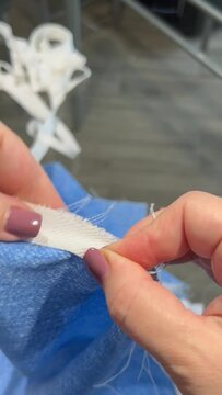 Hand sewing. Threading with a needle in the hands of a woman.