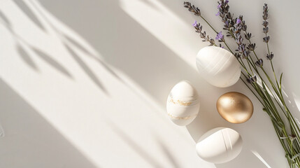 A minimalist Easter flat lay with white and gold-painted eggs simple ceramic decorations and a sprig of lavender on a clean white surface.