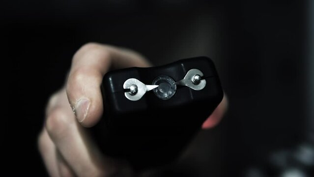 Stun gun in a man's hand, electric discharge, portable shocker, dog repeller. Slow motion camera