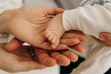 A close-up photo of a small child's leg in his hands. Touching the child's toes. A child's sleep