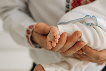 A close-up photo of a small child's leg in his hands. Touching the child's toes. A child's sleep