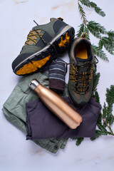 Still life of hiking clothes, boots and aluminum thermos seen from above
