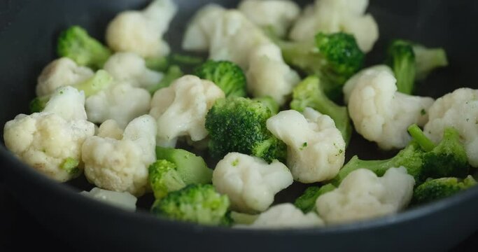 Broccoli and cauliflower cooking in a frying pan. Close up.