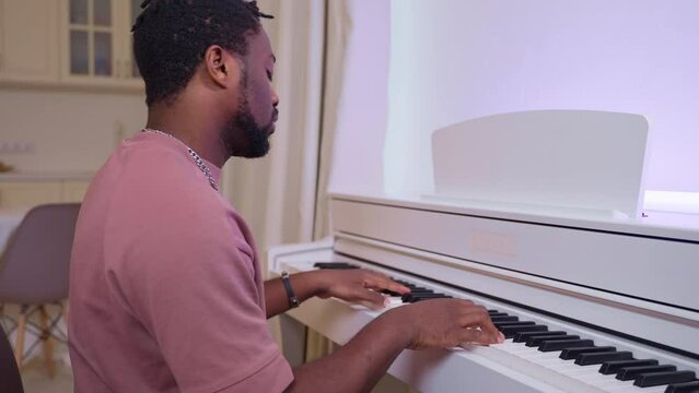 Talanted african american guy pianist practicing playing piano at home.