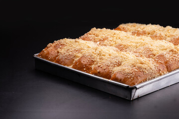 German schneke bread with sweet crumbs in a metal pan on a black table