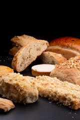various breads and bread rolls with sesame seeds and chestnuts on a black background