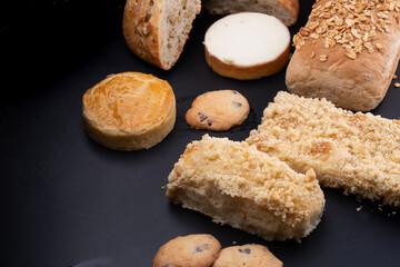 various breads and cakes with cheescake cookie products sesame and chestnuts on black table bakery